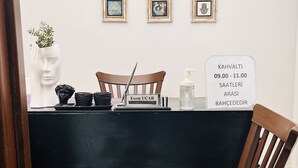 Una habitación con una mesa negra, sillas de madera, un retrato en marco y un cartel con texto.