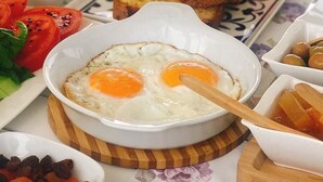 Un desayuno con huevos, tostadas, tomates y una taza de té.
