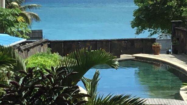 Una piscina con vista sull'oceano e una barca all'orizzonte.