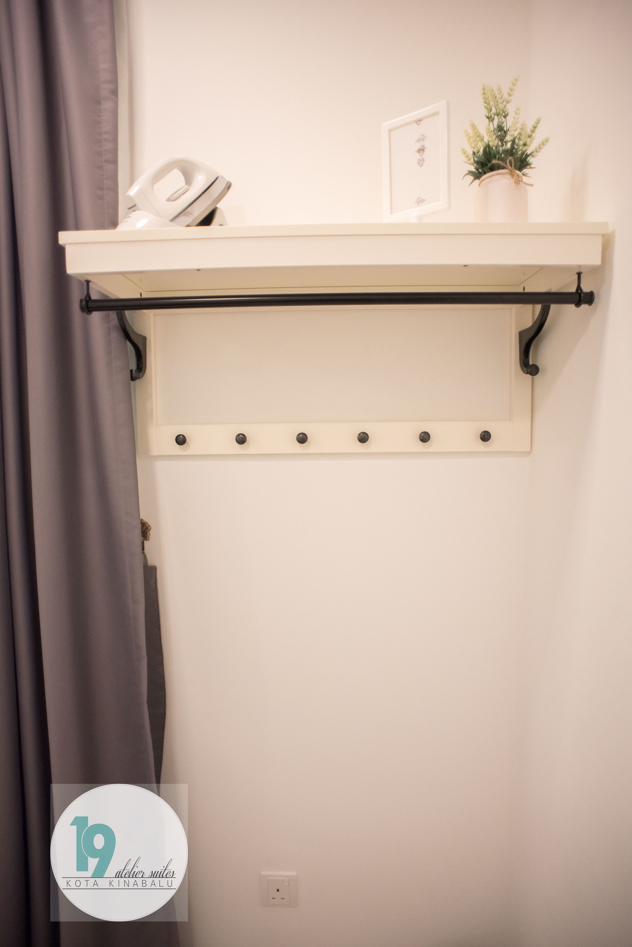 Een wit plank met een zwart metalen frame, een kleine plant in pot en een ingelijst beeld.