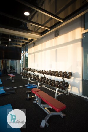 A gym with rows of dumbbells, benches, and exercise equipment.
