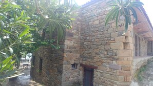 A stone building with a rustic appearance, featuring a small window and a door. - Kastro Konak Boutique Otel (Gökçeada)