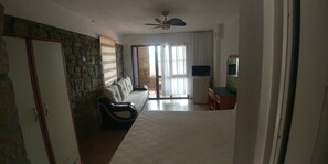 A living room with a stone wall, a sofa, a TV, and a ceiling fan.