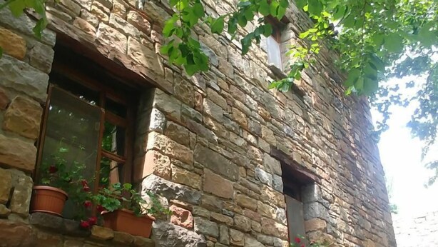 A stone building with two windows, each with a potted plant. - Kastro Konak Boutique Otel (Gökçeada)