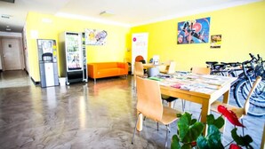A room with a wooden floor, a yellow wall, a table with chairs, a sofa, a refrigerator, and a bicycle. - Residence Igea (Rimini)