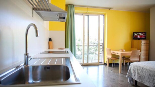 A compact hotel room with a kitchenette, a dining area, and a bed. - Residence Igea (Rimini)