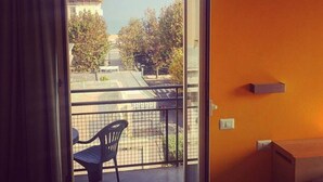 A balcony with a view of a cityscape, a chair, and a small table. - Residence Igea (Rimini)