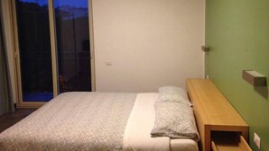 A bedroom with a bed, a wooden bedside table, and a green wall. - Residence Igea (Rimini)