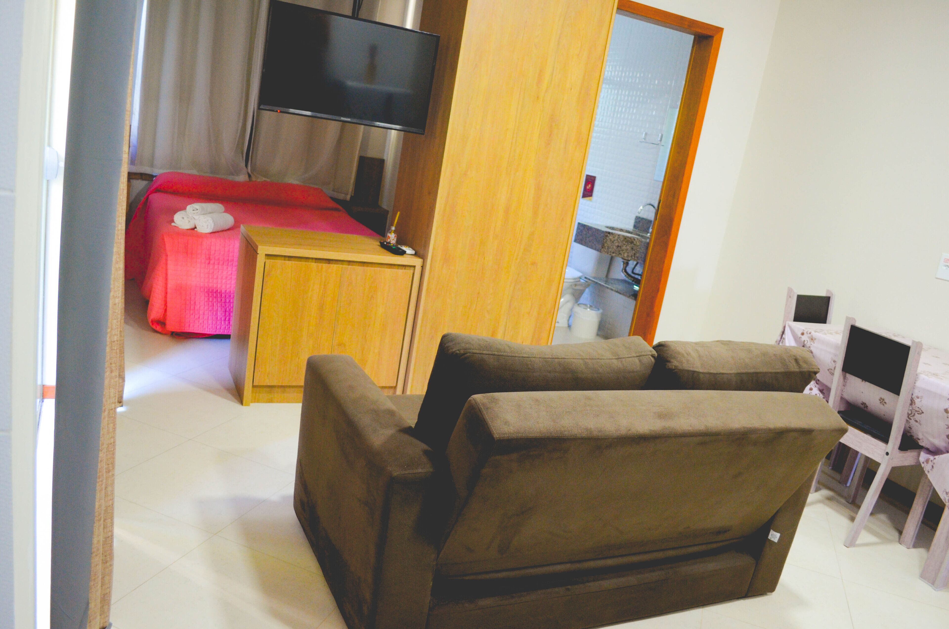 Une pièce comprenant un lit, un téléviseur, une armoire en bois et un canapé marron.