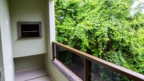 A balcony with a view of dense green foliage. - Canto Dos Passaros Flat Canasvieiras (Florianópolis)
