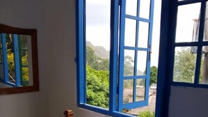 A bedroom with a bed, a window with blue shutters, and a view of greenery outside. - Nature Mount Pavilion Ella (Ella)