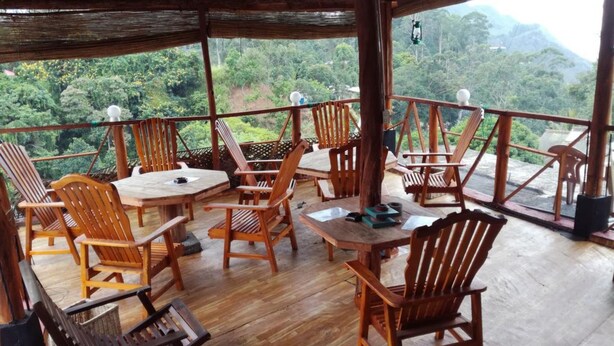 A wooden deck with tables and chairs, overlooking a lush forest and mountains. - Nature Mount Pavilion Ella (Ella)