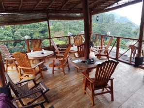 A wooden deck with tables and chairs, overlooking a lush forest and mountains. - Nature Mount Pavilion Ella (Ella)