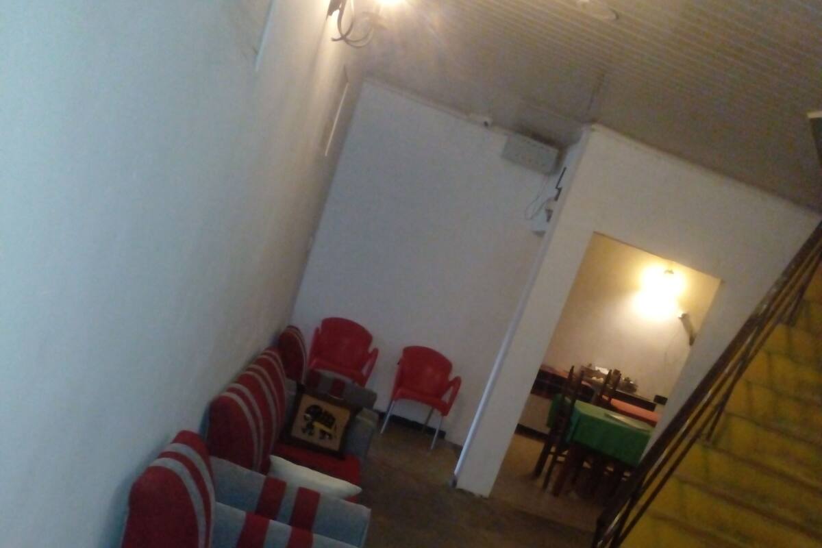 A room with a staircase, a dining area, and several red and grey chairs.