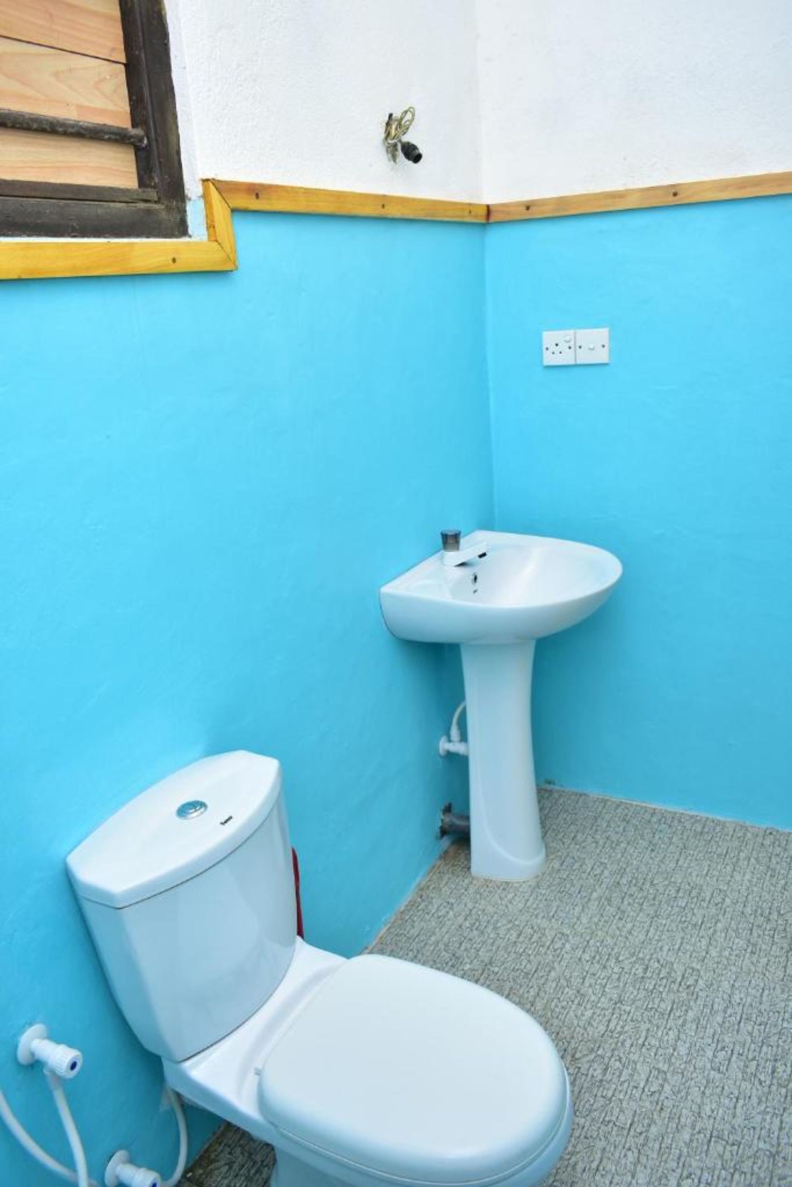 Une petite salle de bain avec des toilettes, un lavabo et une fenêtre dotée de volets en bois.