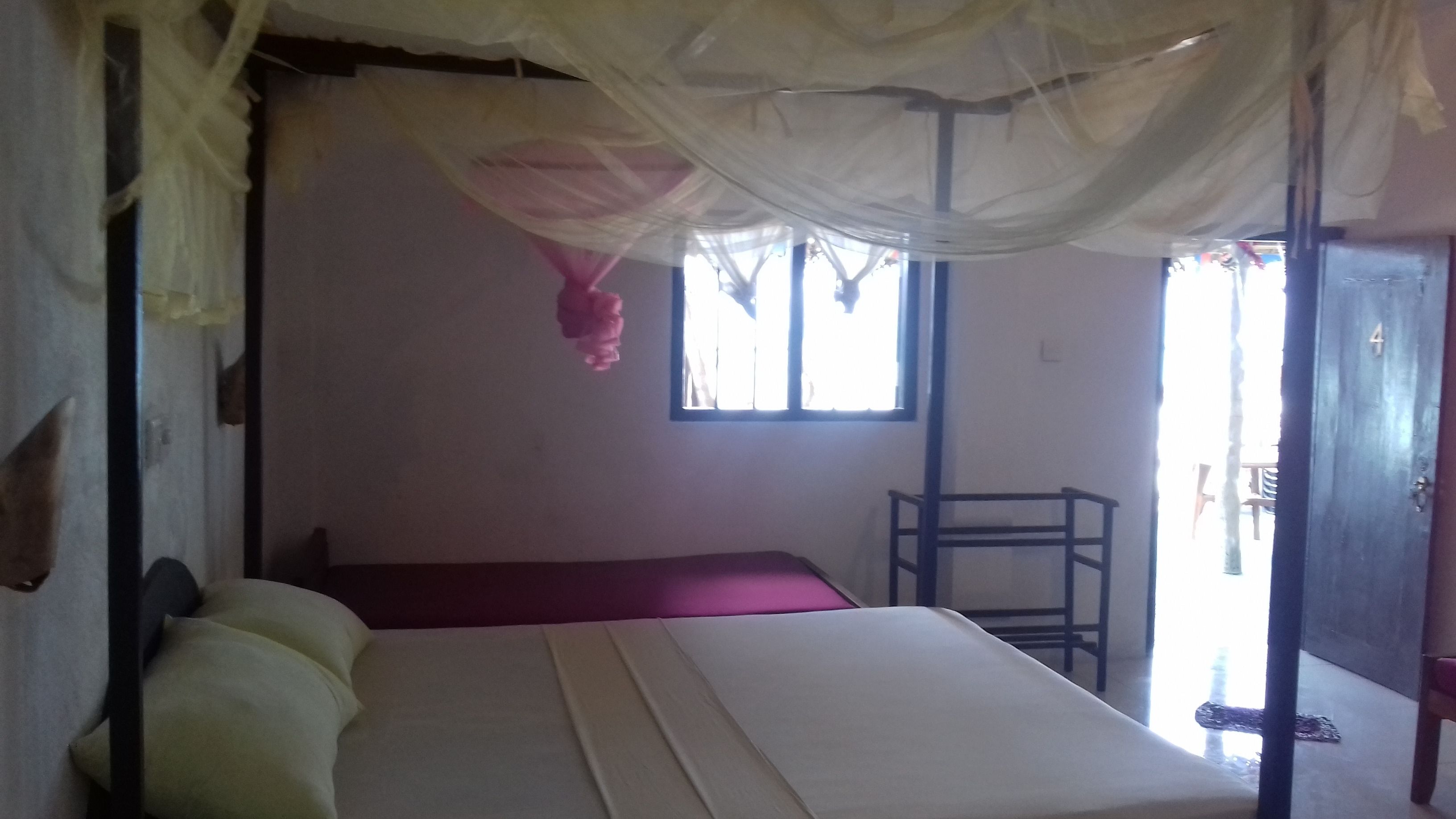 A room with a bed, a window, and a door.