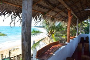 Uma cabana à beira-mar com telhado de palha, com vista para o oceano.