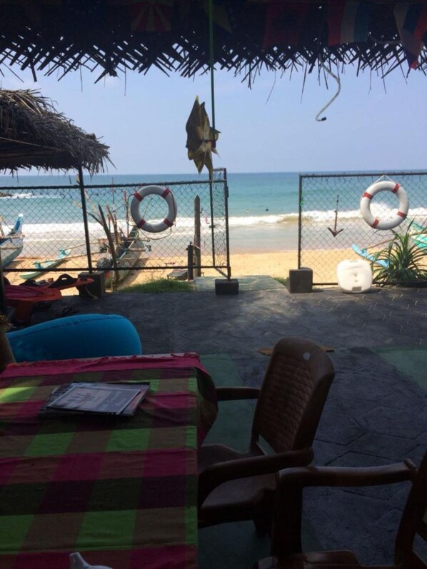 Un espacio de estar frente a la playa con mantel a cuadros, sillas y vistas al océano.