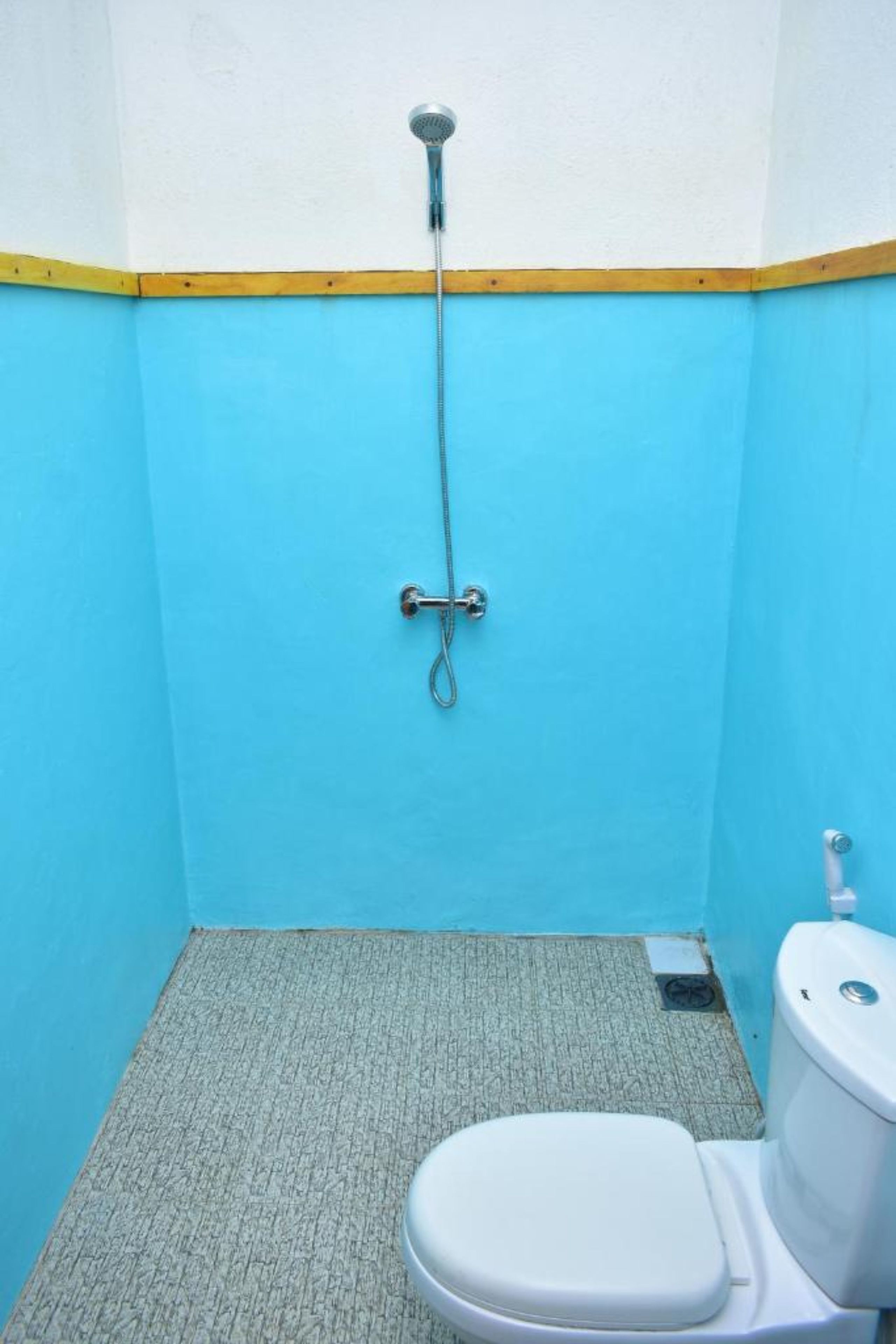 A small, single-occupancy bathroom with a toilet, a shower, and a sink.