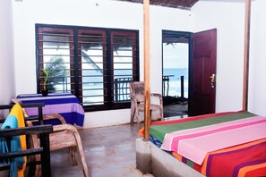 A room with a bed, a chair, a table, and a window with a view of the sea. - villa crocodile beach (Hikkaduwa)