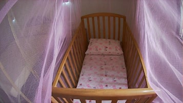 Una cuna de madera con una sábana rosa y un cojín con estampado floral.