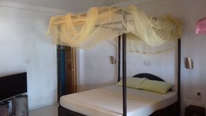 A single bed with a canopy, a bedside table, a power outlet, and a wall socket. - villa crocodile beach (Hikkaduwa)