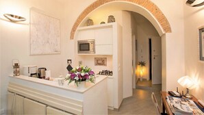 Una cocina moderna con armarios blancos, un microondas y una pequeña isla con un florero.