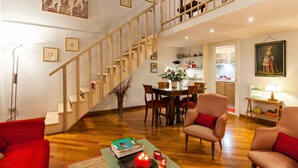 A spacious living room with a wooden staircase, a dining area, and a kitchen in the background. -  Rome center Campo de Fiori great reviews within walking distance to everything! (Roma)