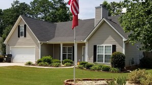 Een woonhuis met een verzorgd gazon, een garage en een vlaggenmast met de Amerikaanse vlag.