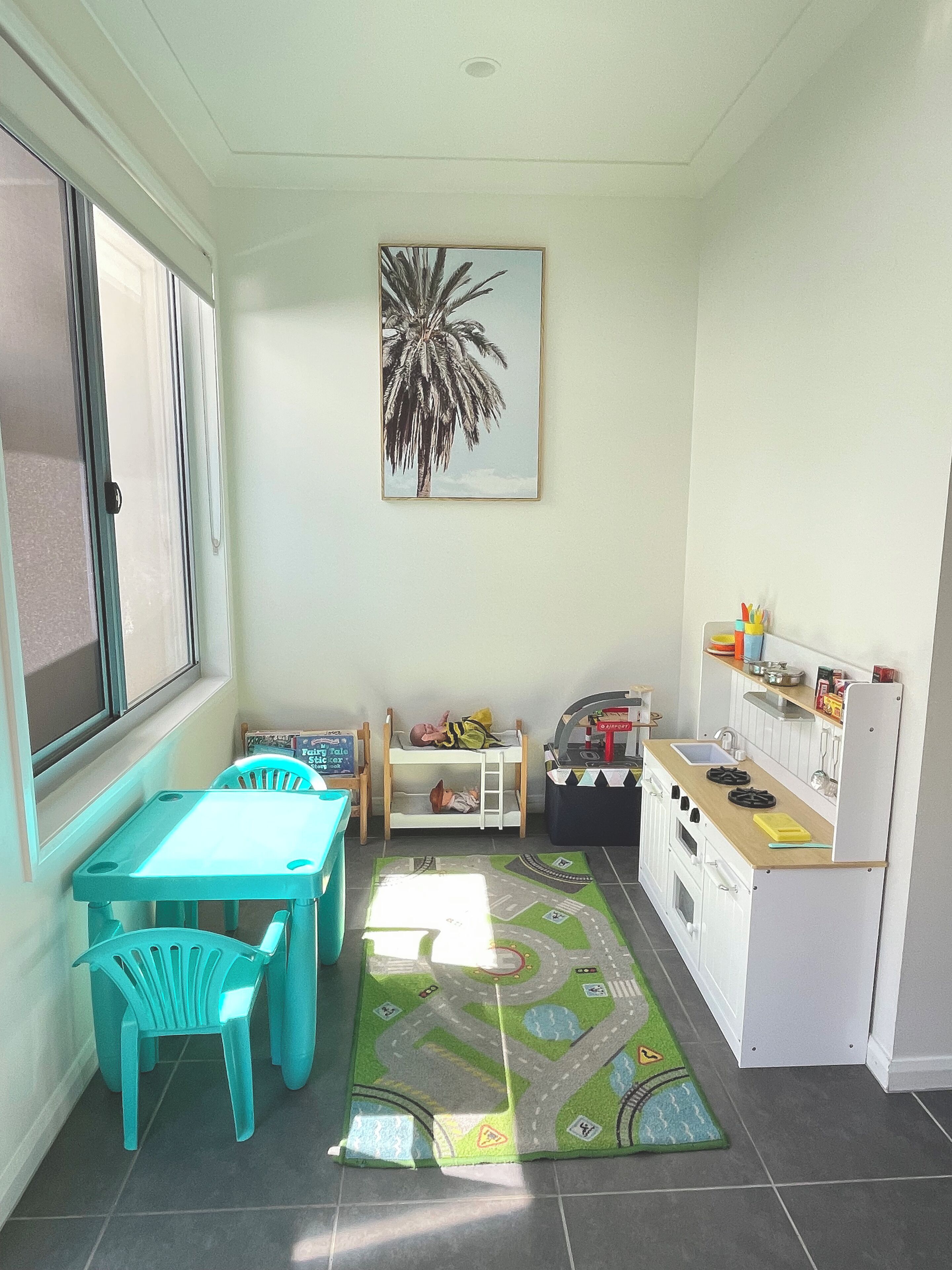A compact kitchen with a dining area, a children's play area, and a window providing natural light.