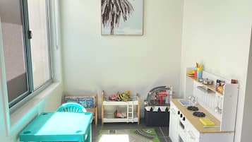 A compact kitchen with a dining area, a children's play area, and a window providing natural light.