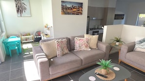 Ein Wohnzimmer mit einer Couch, einem Couchtisch, einem kleinen Tisch mit Pflanze und einem Stadtbild an der Wand.