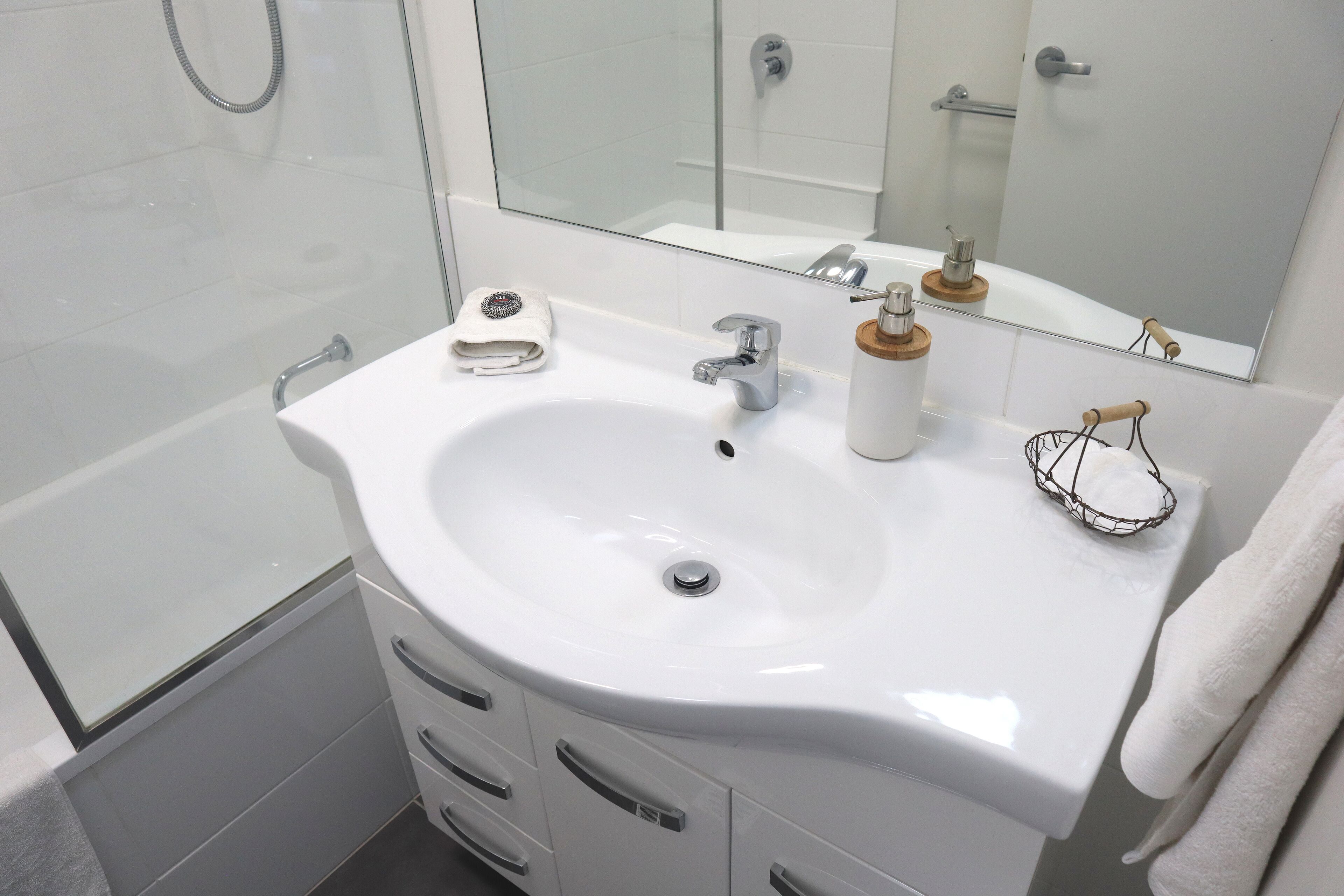 A modern bathroom with a white sink, a mirror, and a bathtub.