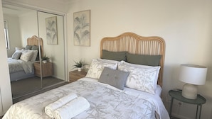 Ein Schlafzimmer mit Bett, Spiegel, Nachttisch, Lampe und Wandbildern.