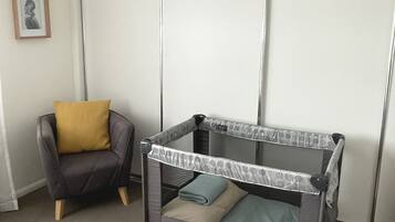 Cozy retreat with a single bed, crib, and comfortable armchair for a family-friendly stay.