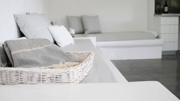 Un dormitorio moderno y minimalista con una cama blanca, almohadas grises y blancas, y una cesta de mimbre sobre la cama.