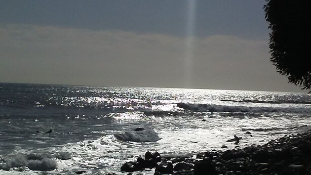 Ein Strand mit Wellen und blauem Himmel.