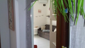 Ein Wohnzimmer mit grauem Sofa, einem kleinen weißen Tisch und einer Wand mit motivierenden Sprüchen.