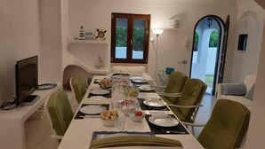 Een eethoek met een tafel voor vier personen, stoelen, een televisie en uitzicht op de omgeving.