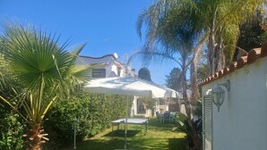 Een terras met een tafel, stoelen, een fiets en een witte parasol.