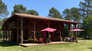 Uma cabana de madeira com varanda coberta, área de estar externa e rede.