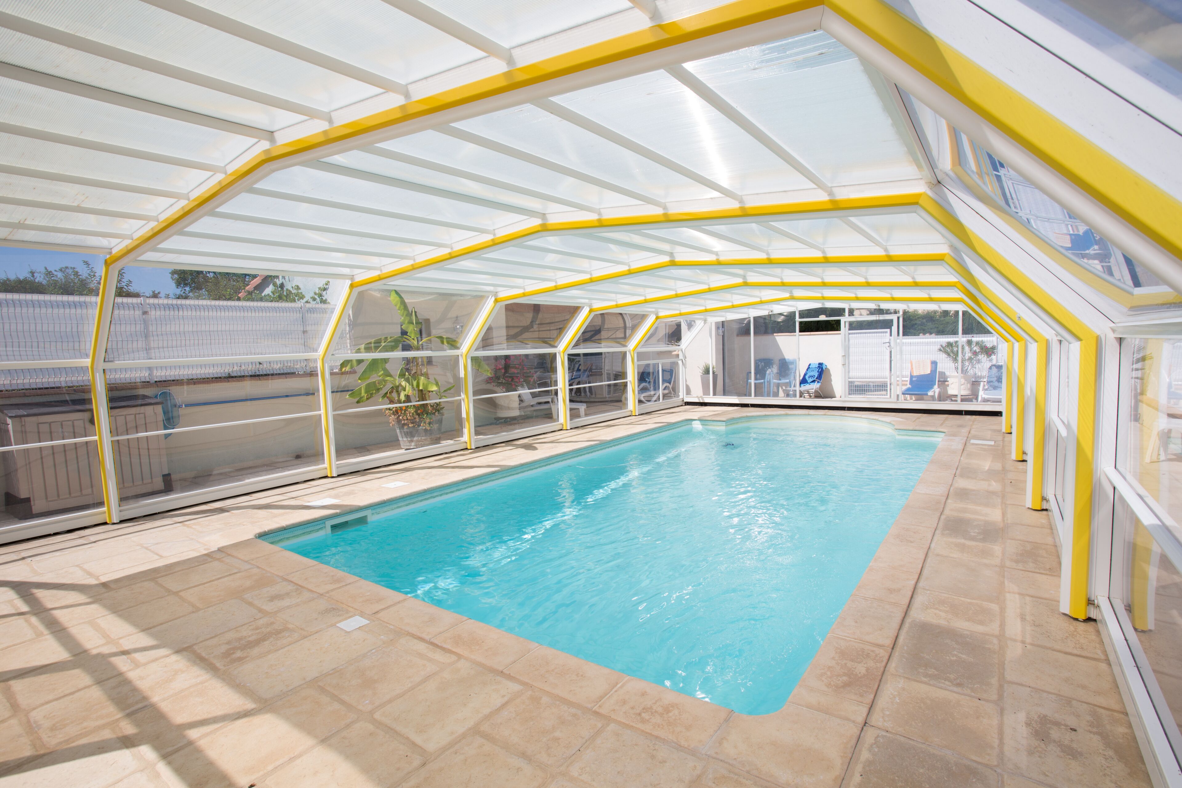 Une piscine intérieure dotée d’une paroi vitrée et de rampes de sécurité jaunes.