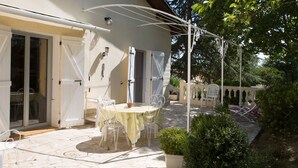 A patio with a table and chairs, a white fence, and potted plants. - House with all mod cons, covered and shared pool - quiet and green setting (Loubers)