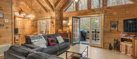 A cozy cabin interior with a sofa, dining table, and a kitchen area.