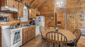 Ein Holzblockhaus-Interieur mit Küche, Esstisch und Stühlen.
