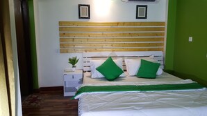Un dormitorio con cabecera de madera, ropa de cama blanca y almohadas verdes.