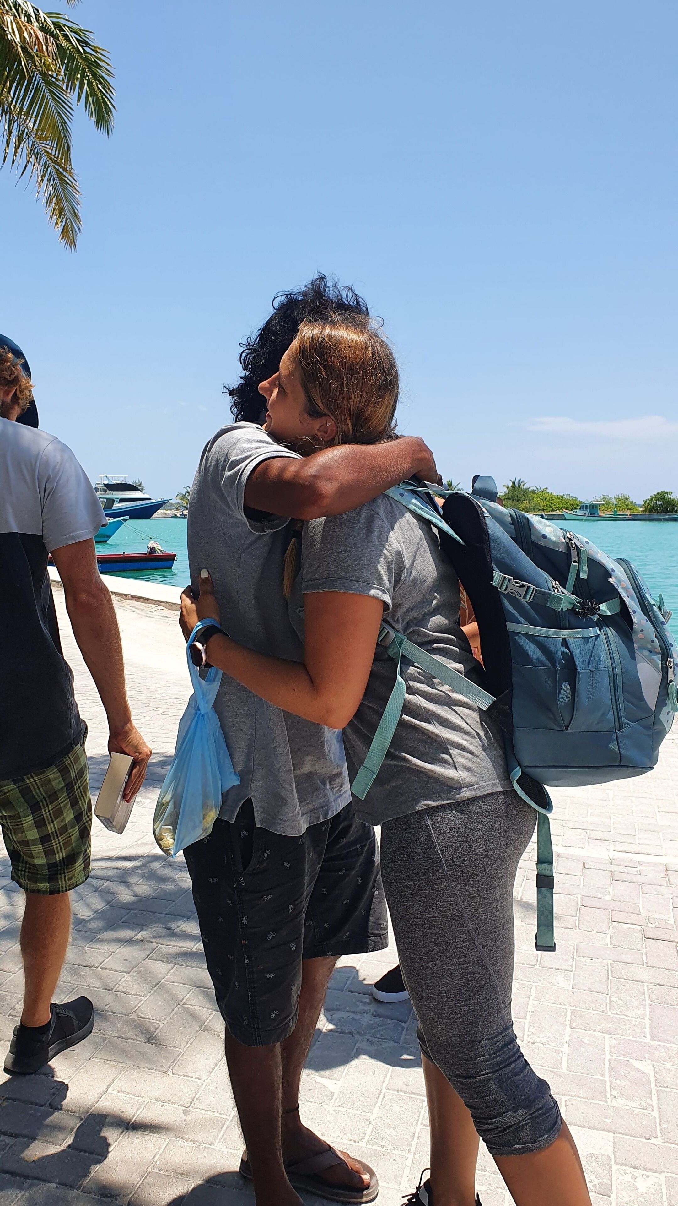 A person hugging another person with a blue backpack.