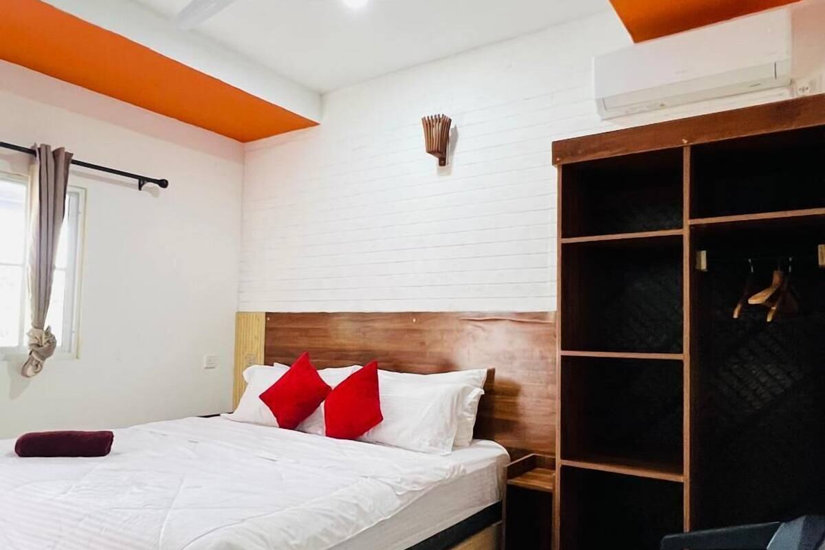 Un dormitorio moderno con una cama de madera, un ventilador de techo, un armario y un escritorio pequeño con una silla.