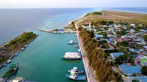 Vista aérea de un pueblo costero con un puerto deportivo, barcos y casas.