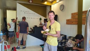 Un hombre sostiene un coco en una habitación con una recepción y un reloj en la pared.